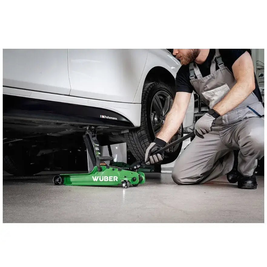 Biljekk lavprofil 2,5t, grønn metalljekk i bruk under hvit bil med mekaniker i arbeidsklær og hansker.