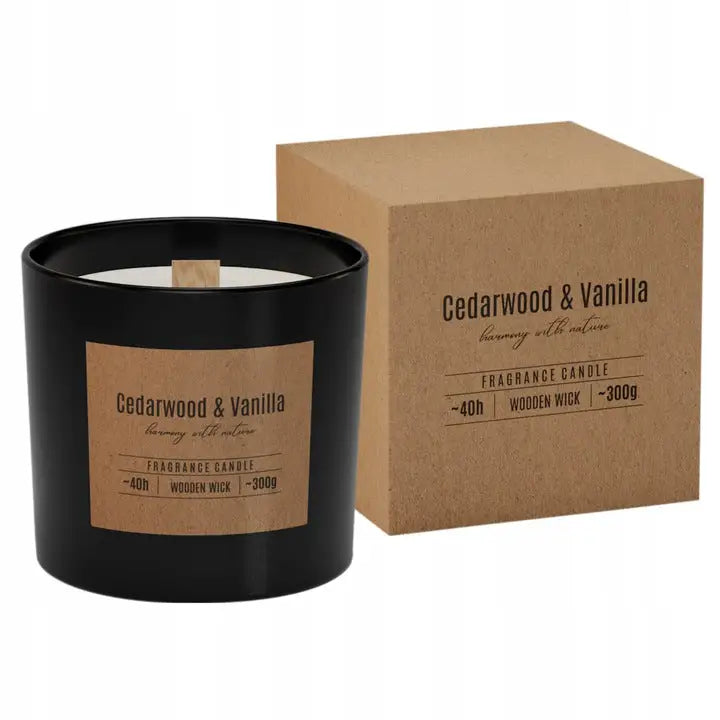 Bispol stearinlys med treveke, sort glass og trefarget etikett, foran brun eske med samme design.