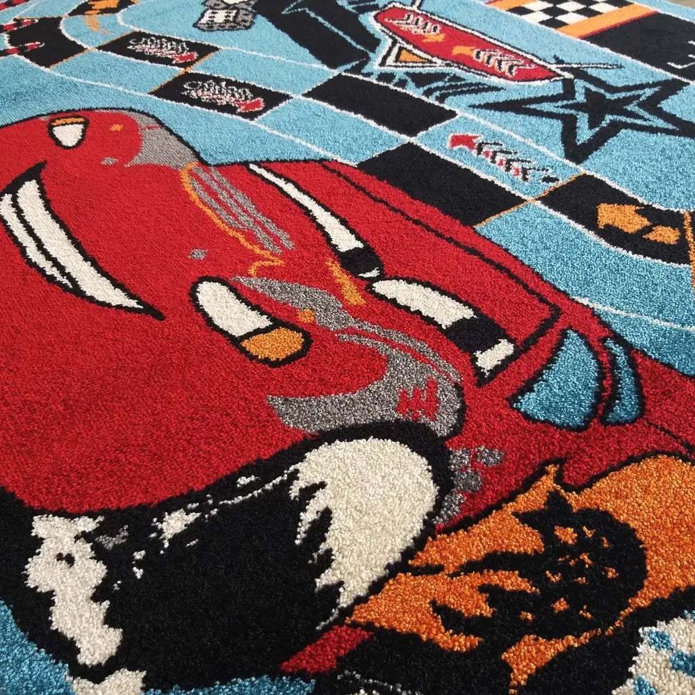 Blå Bella barneteppet med tegneseriebiler, nærbilde som viser stoffets struktur og klare farger.