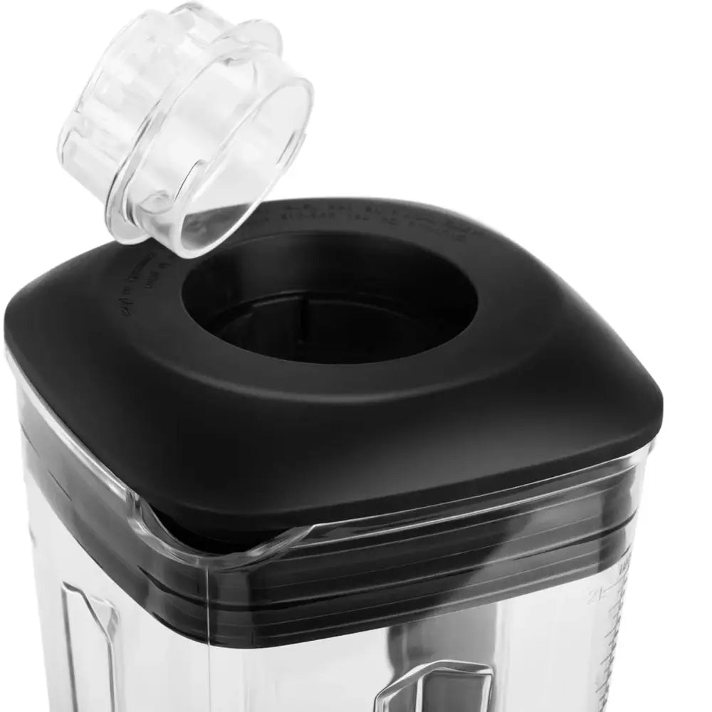Blender med krus og sort lokk, sett skrått ovenfra med løftet gjennomsiktig lokk på lokkets åpning.