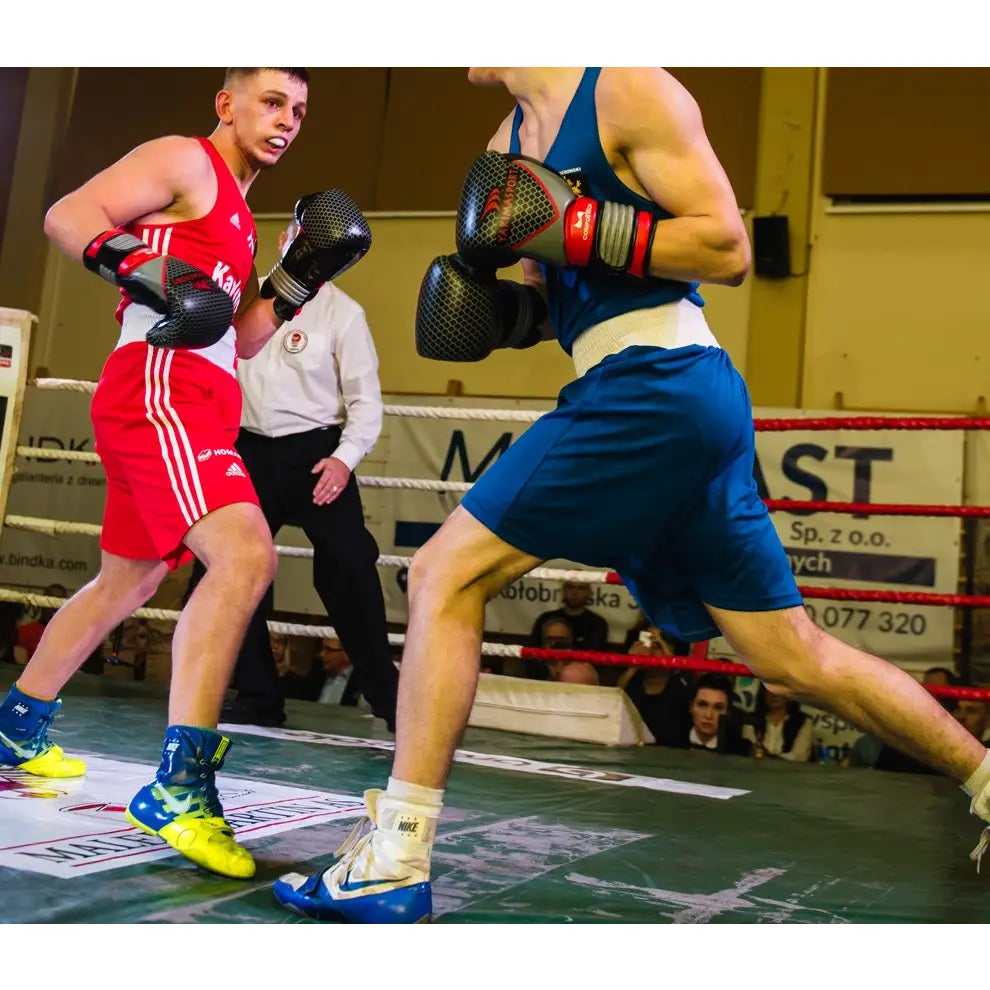 Boksehansker av ekte skinn PRO SPIDER i bruk, to boksere i kamp med synlige hansker og ringtau.