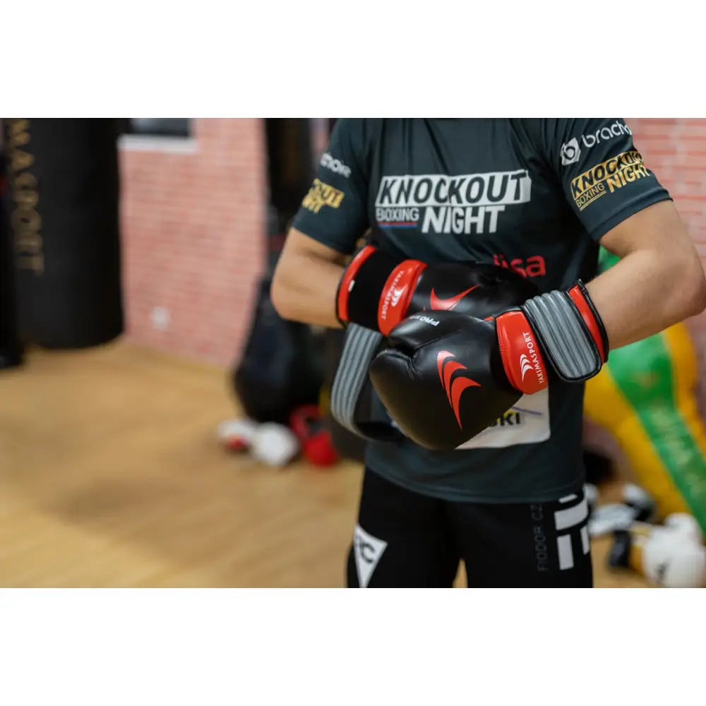 Boksehansker i ekte skinn PRO SPIDER, svarte med røde detaljer, brukt under trening i boksemiljø.