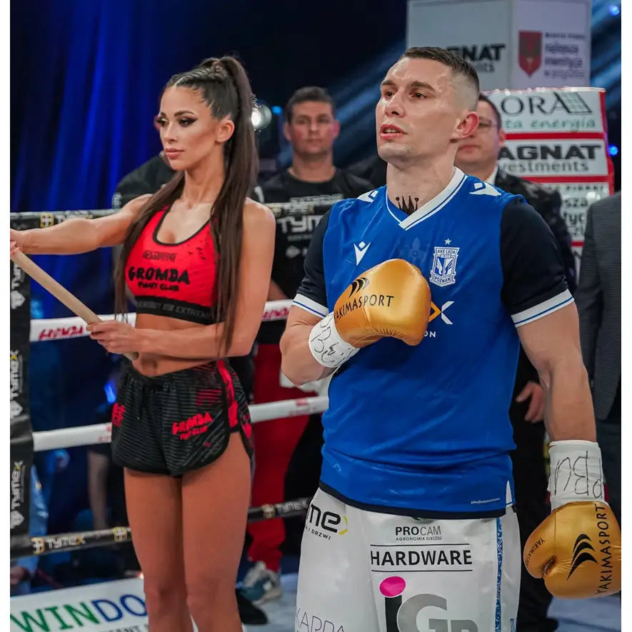 Boksehansker TIGER GOLD, gul modell i bruk av mann i boksering, én hånd hvilende på brystet.