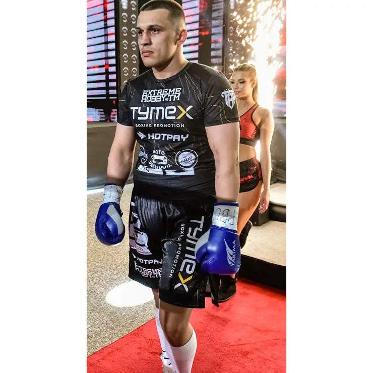 Boksehansker WOLF BLUE V 10 oz, bæres av mann i svart bokseutstyr på rødt teppe i lyst treningsrom.