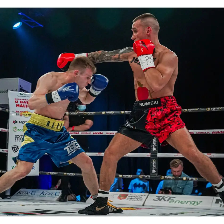 Boksehansker WOLF i rødt, brukt av bokser i aksjon med røde og svarte shorts under kamp i boksering.