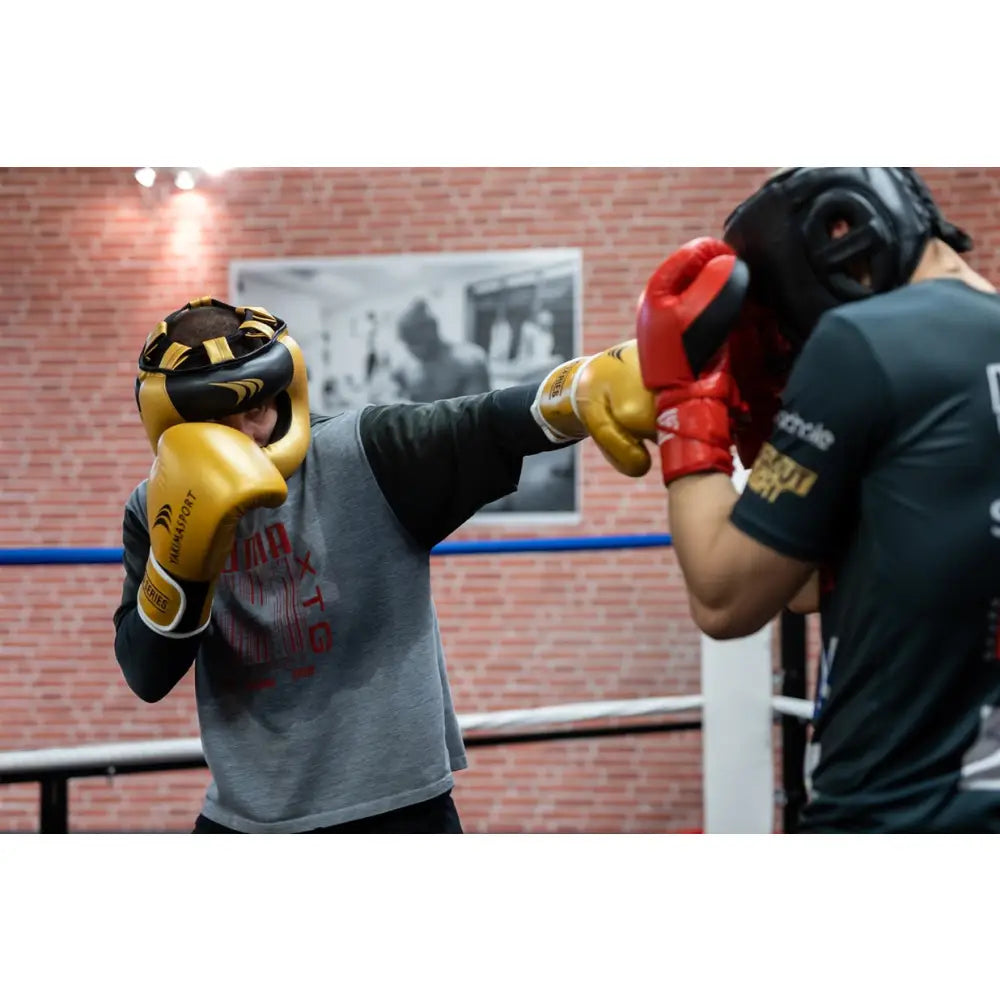 Boksehansker TIGER GOLD, gullfargede hansker i bruk under sparring, sett fra siden i boksetrening.