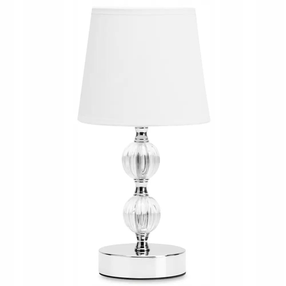 Bordlampe med hvit skjerm, sølvfot og to rillede glasskuler på stammen, frontvisning mot hvit bakgrunn.