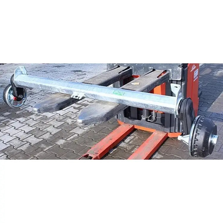 Aksling for tilhenger med to ulike hjul montert, vist på rød palletruck utendørs på belegningsstein.