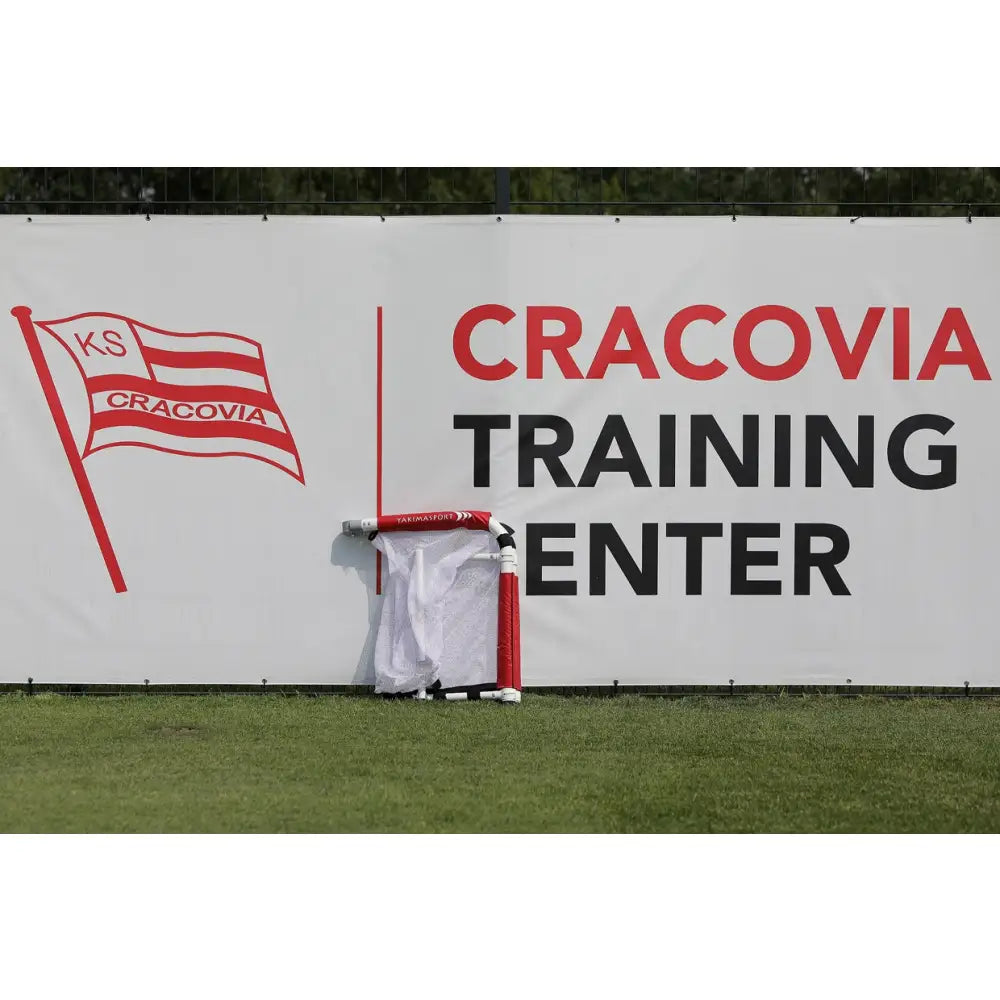 Brettport Akademiet fotballmål, sammenlagt på gress foran Cracovia Training Center-skilt, røde og hvite detaljer.