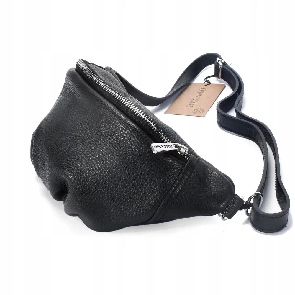 Dame mageveske i svart strukturert skinn, skrå sidevisning med synlig glidelås, stropp og skinnmerkelapp.