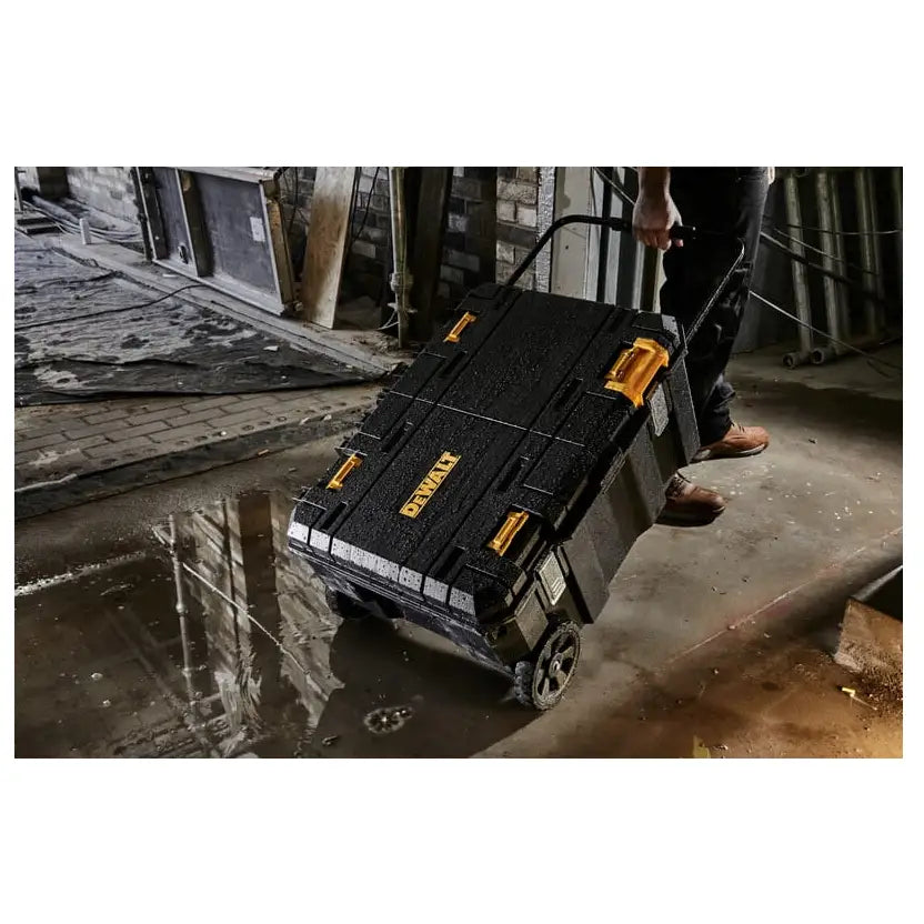Dewalt stor Tstak koffert med to skuffer og hjul, trekkes gjennom vått industrigulv av en person.