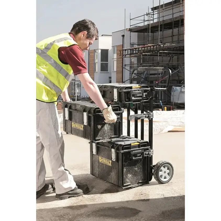 Dewalt Tough System verktøykasser stablet på tralle i bruk utendørs på byggeplass av person med refleksvest.
