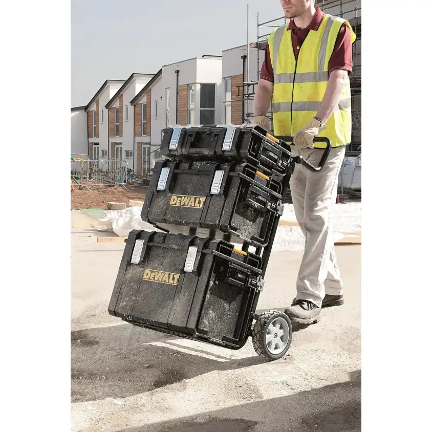 Dewalt Tough System verktøykasser på tralle, kjørt av arbeider foran byggematerialer på byggeplass.