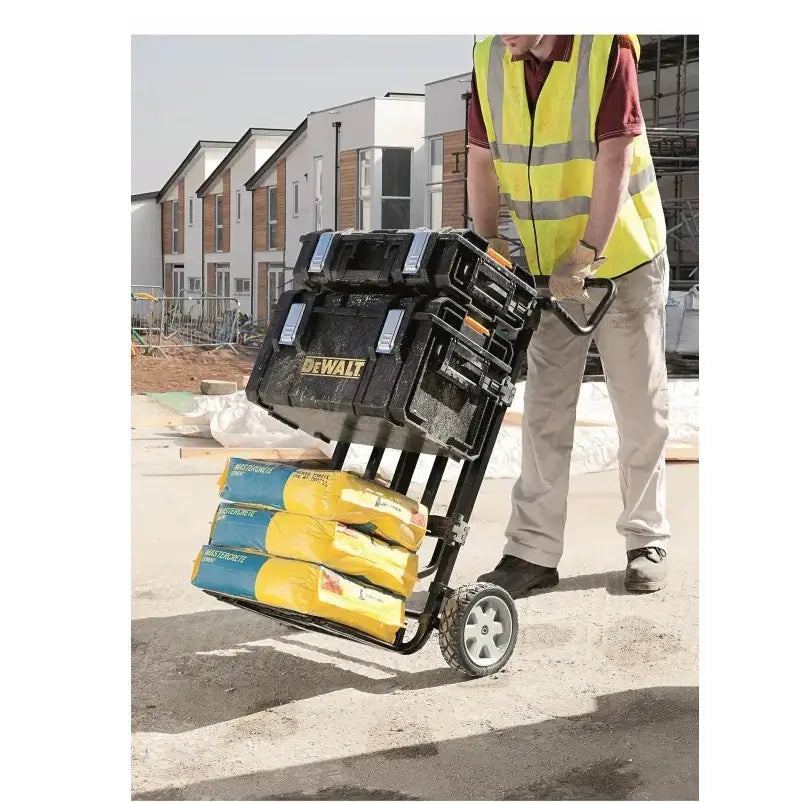 Dewalt Tough System verktøykasser på tralle med grå hjul, trilles av person i refleksvest på byggeplass.