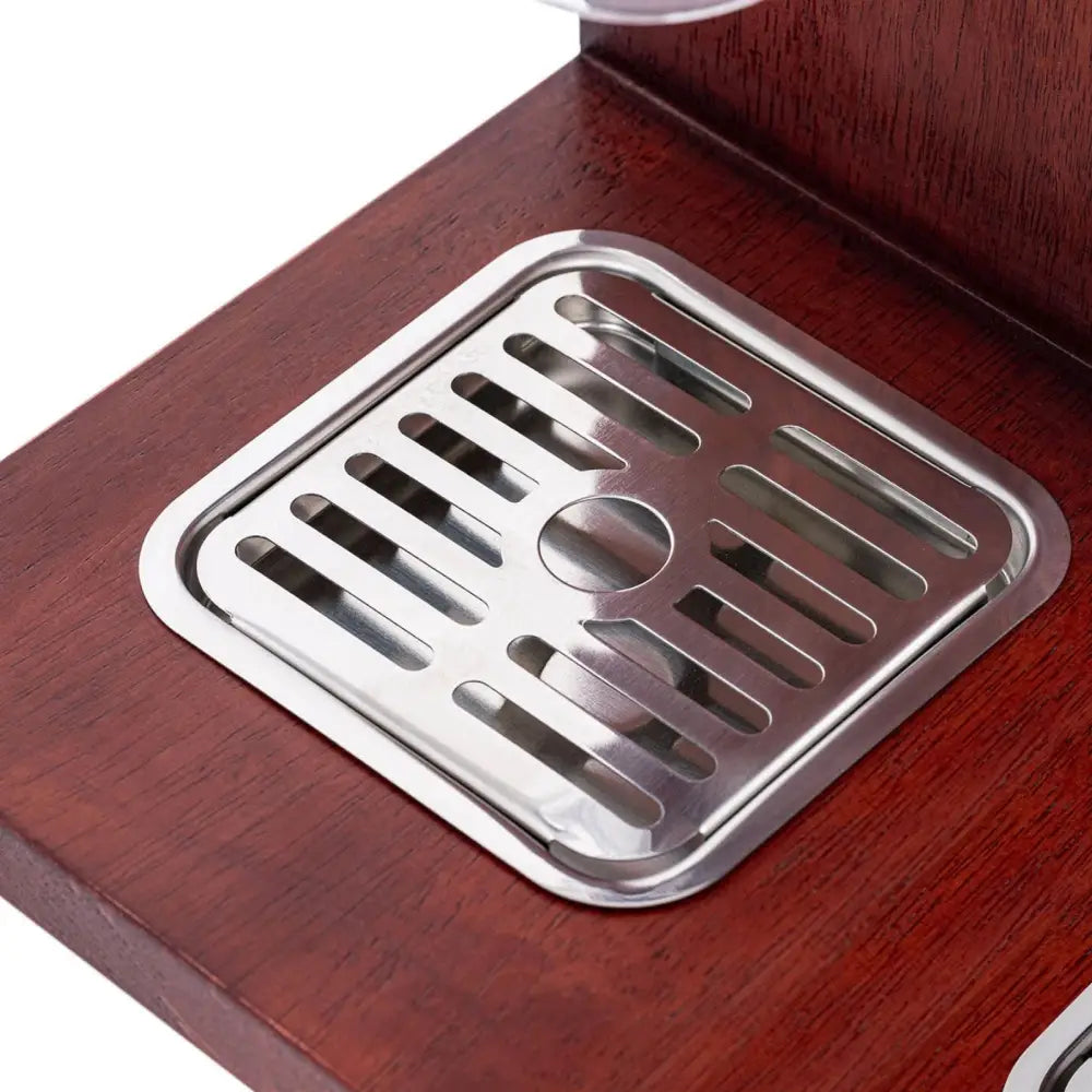 Dryppbrett i rustfritt stål for dispenser, nærbilde som fremhever struktur og plassering på mørkt treverk.