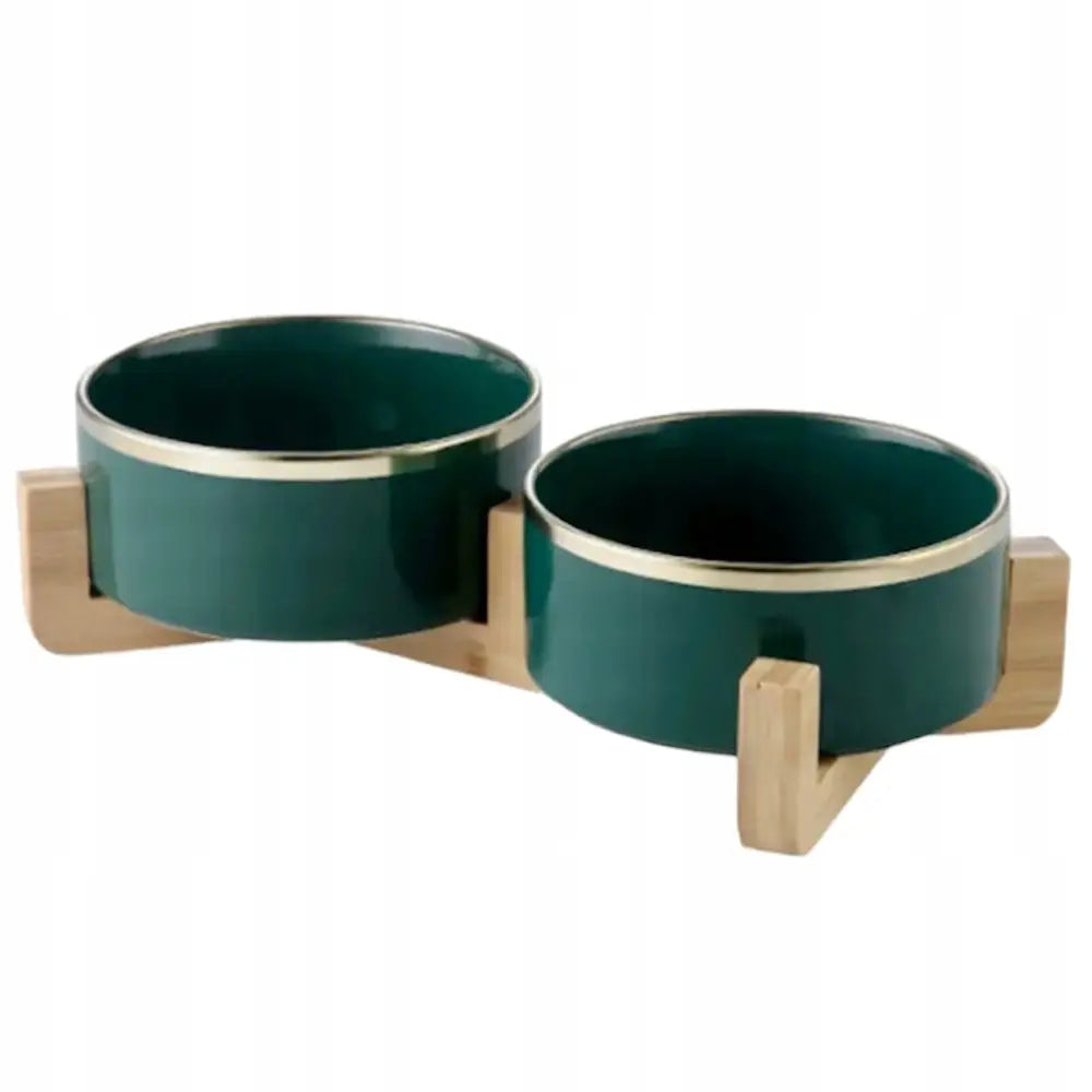 Dobbel keramisk matskål for hund og katt, grønne skåler med gullkant i lys trestativ, sett skrått forfra.