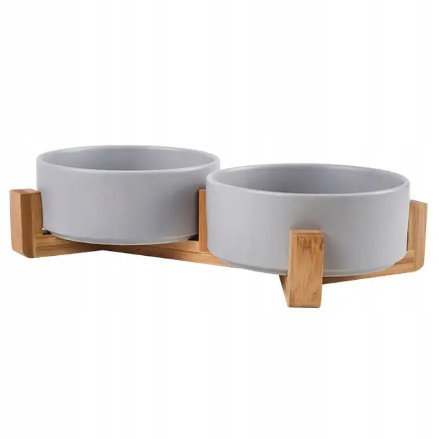 Dobbel keramisk skål for hund og katt, grå skåler i lys trefarget holder sett skrått mot hvit bakgrunn.
