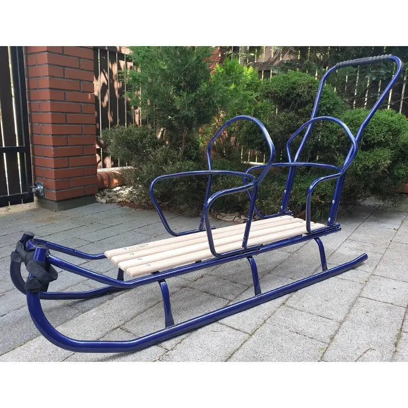 Dobbel tandem akebrett i blått med metallramme, to seter og trespiler, sett fra siden på uteplass.