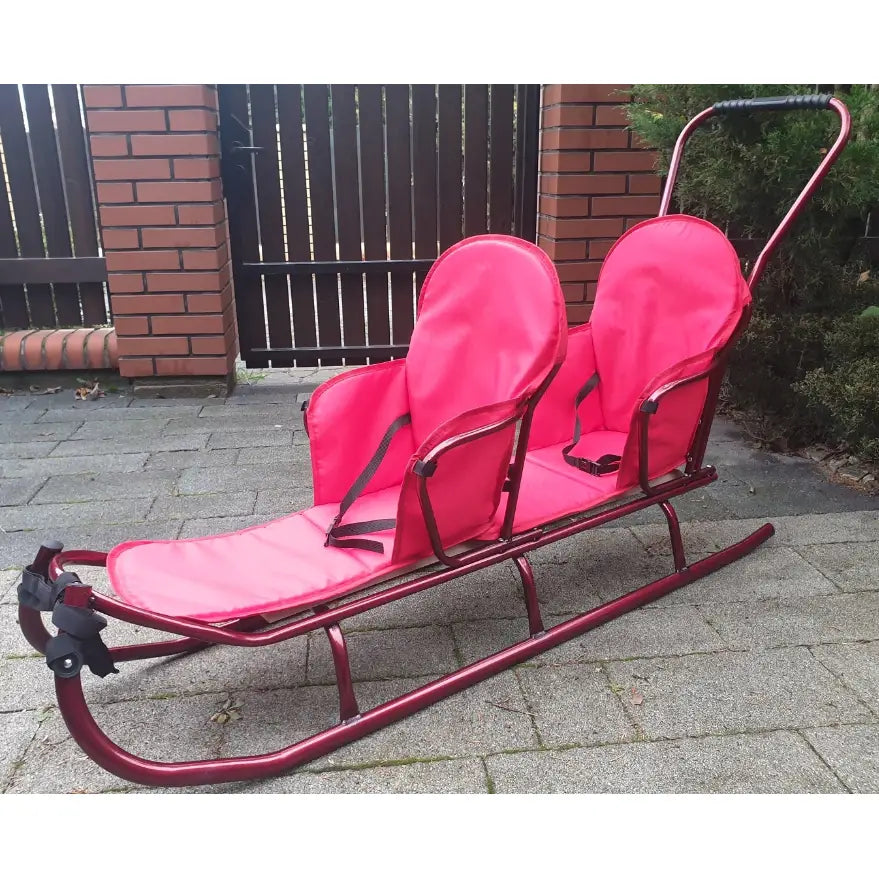 Dobbel tandem akebrett i rødt med to seter, sorte stropper og metallramme, sidevisning på gårdsplass.