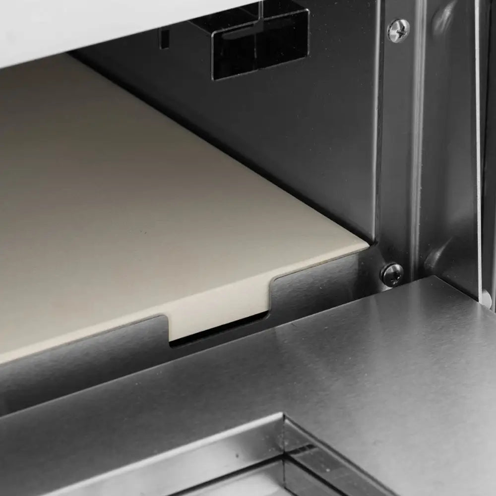 Dobbelkammer pizzaovn, nærbilde av lys steinplate med utskjæringer i rustfritt ovnsrom.