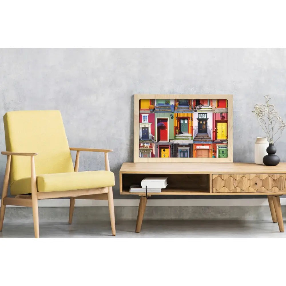 Dører i Norge-plakat på lyst trebord, med lysegul stol og lys grå vegg i bakgrunnen.