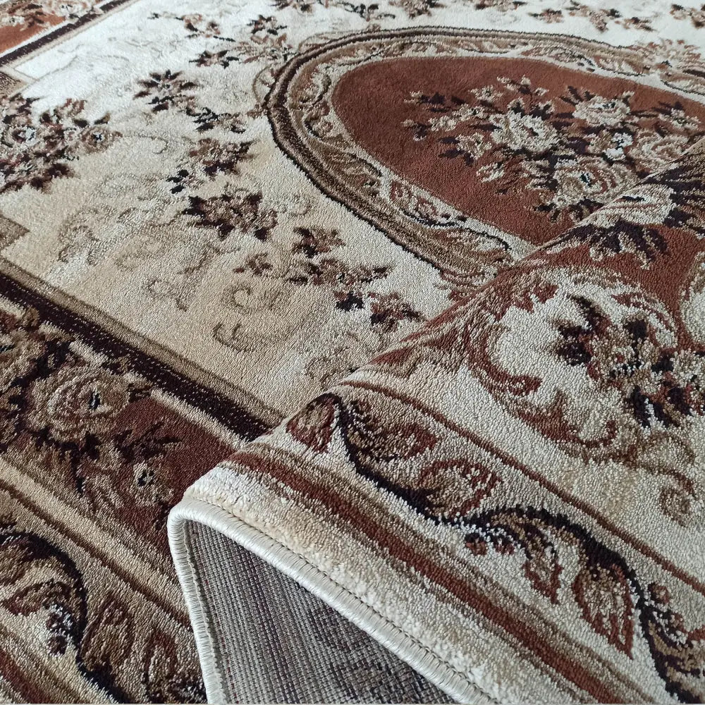 Eksklusivt orientalsk teppe i beige og brunt, nærbilde av tekstur og detaljert mønster med bøyd kant.