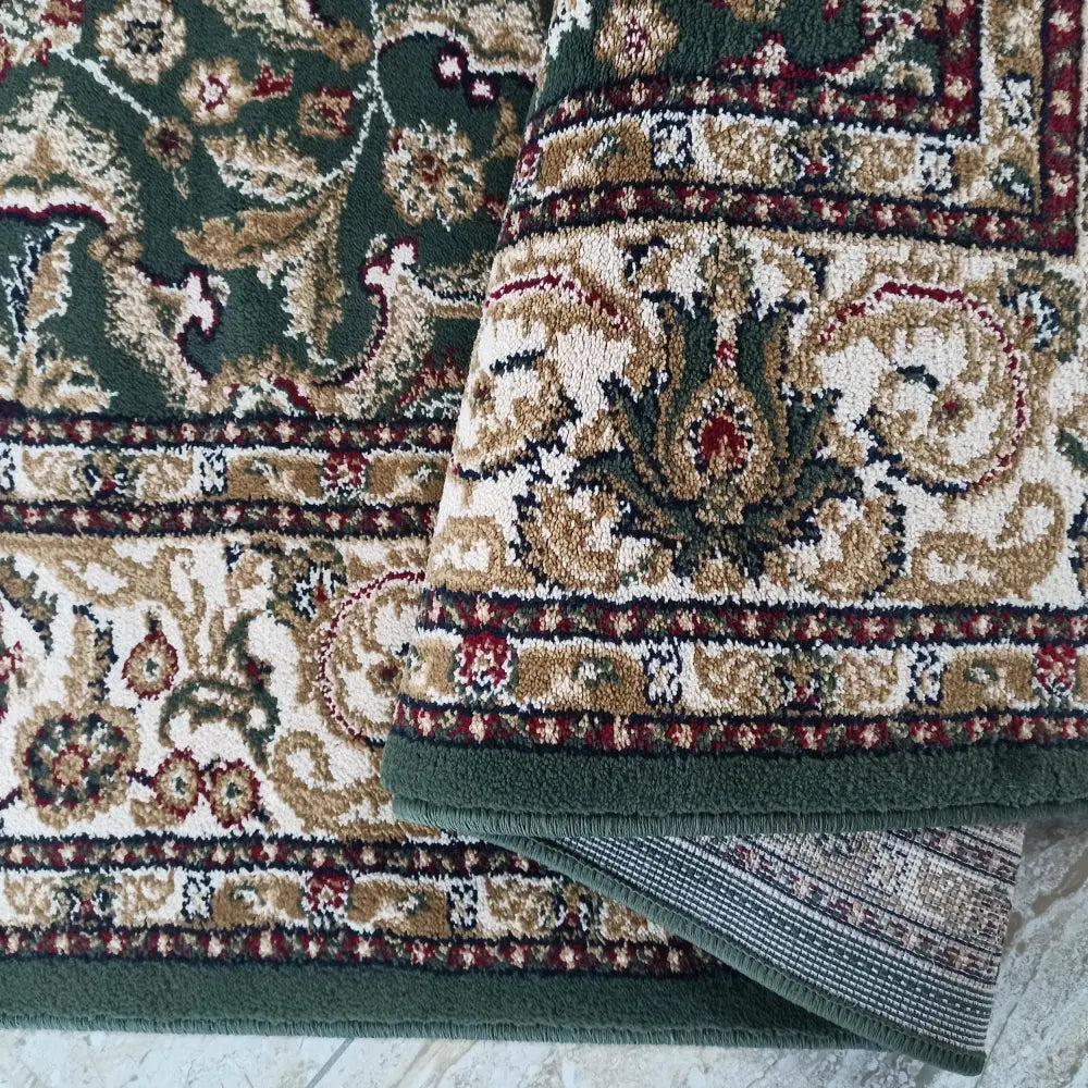 Eksklusiv grønn teppe, nærbilde av hjørne med orientalsk mønster og synlig bakside.