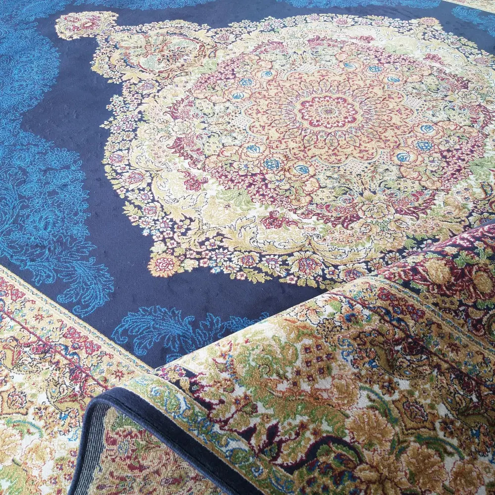 Eksklusivt Qum Silk Tepe, nærbilde av marineblått teppe med detaljerte mønstre og oppbrettet hjørne.