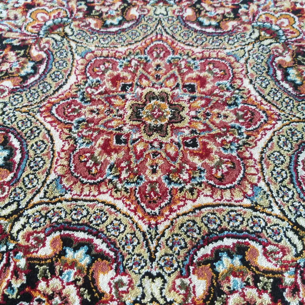 Eksklusiv rød teppe 200 x 300 cm, nærbilde av blomstermotiv med røde, blå og sorte detaljer i tekstur.