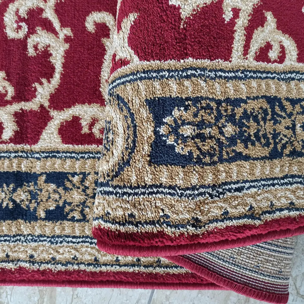 Eksklusivt rødt teppe, nærbilde av burgunder, beige og mørk blå kant med klassisk orientalsk mønster.