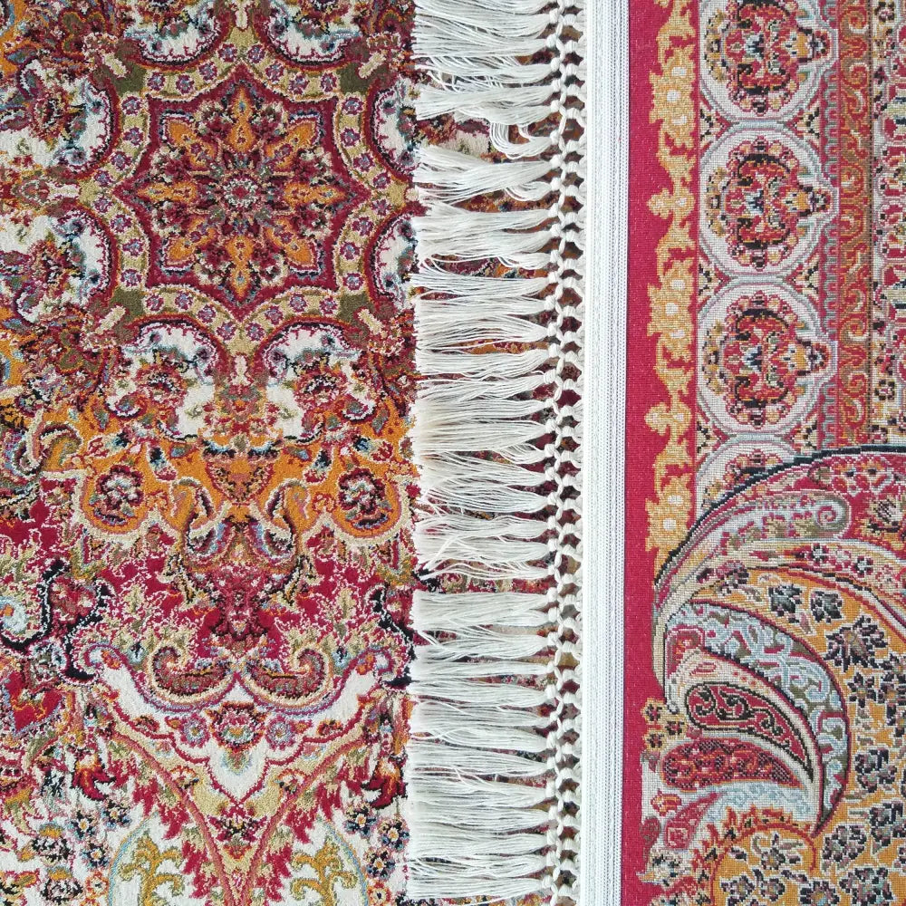 Eksklusivt teppe i røde, gule og hvite toner, nærbilde som fremhever frynser og orientalsk mønster.