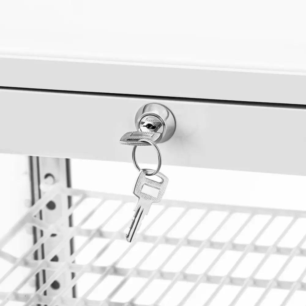 Sølvfarget nøkkel i lås på hvitt eksponeringskjøleskap, nærbilde av låsemekanisme og nøkkelring.