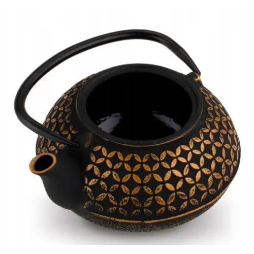 Elegant tekanne i støpejern med gullmønster, sett skrått ovenfra med åpen topp og solid bøylehåndtak.