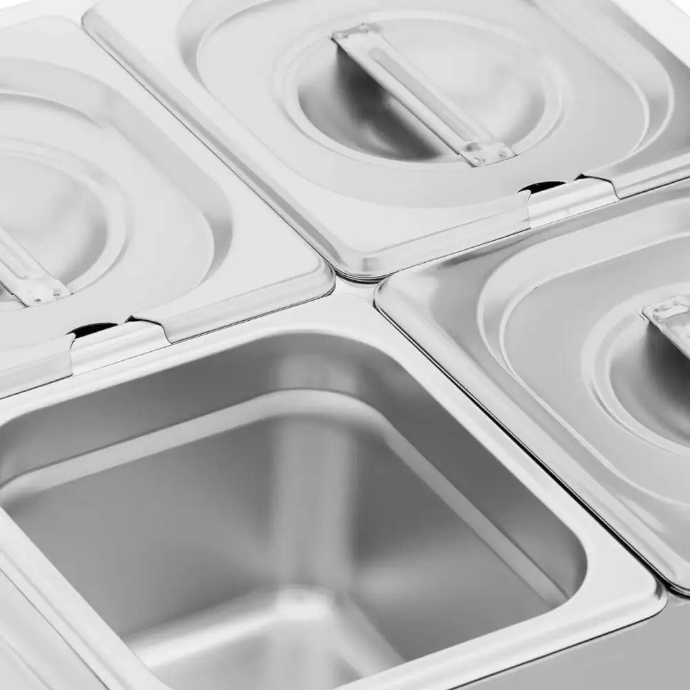 Elektrisk fondueapparat med fire firkantede stålkummer, én åpen og tre med lokk og håndtak, sett ovenfra.