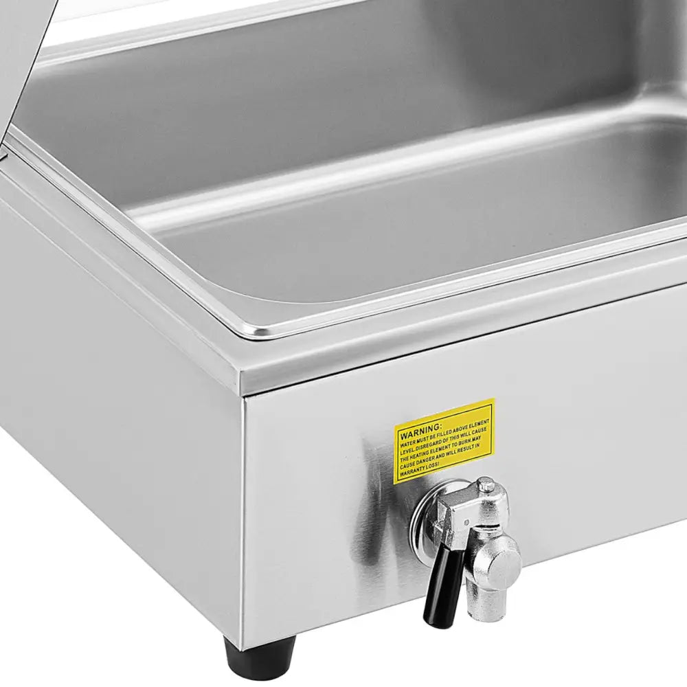 Elektrisk buffetvarmer med kran, skråvisning som fremhever tappkran, gul advarselslapp og solide plastføtter.