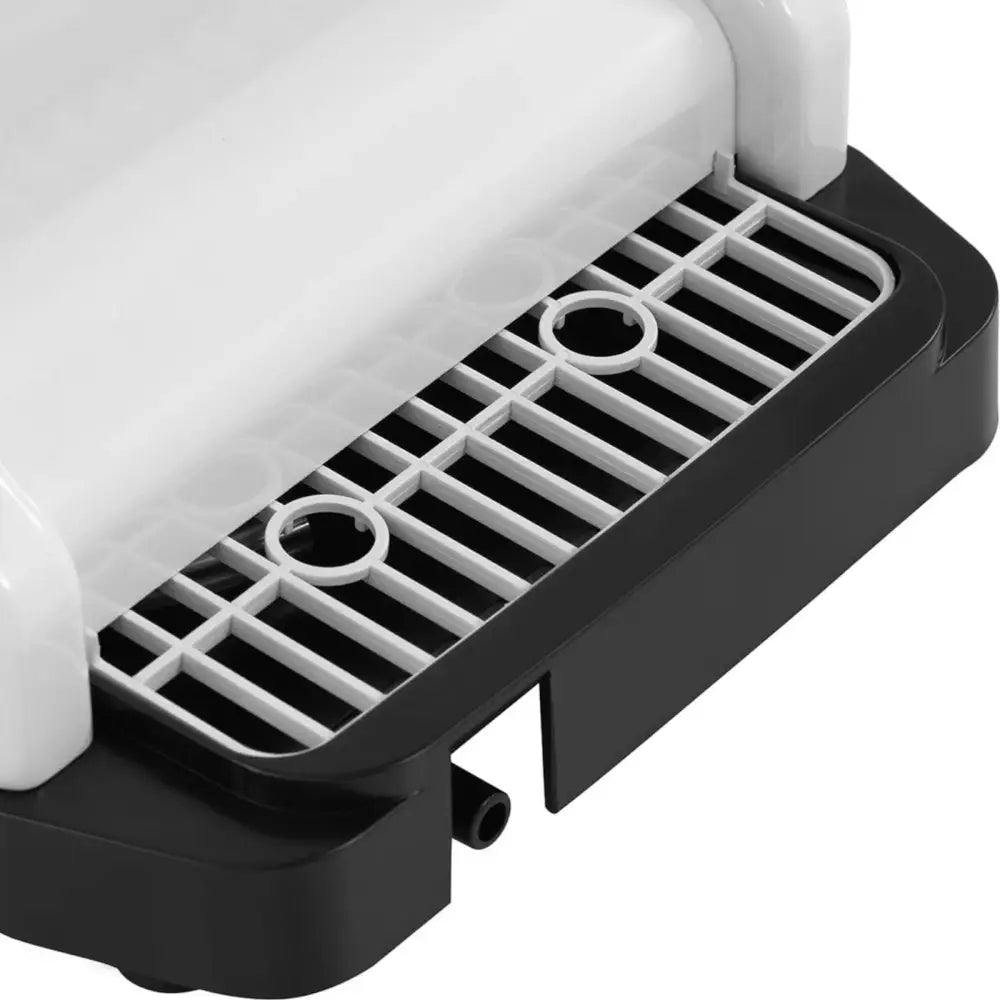 Elektrisk iskvern, nærbilde av hvit og svart plastdel med lysegrå gitterrist og to runde åpninger.