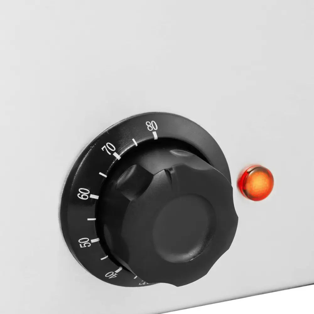 Elektrisk matvarmebeholder, nærbilde av sort dreieknapp med graderinger og oransje indikatorlampe.