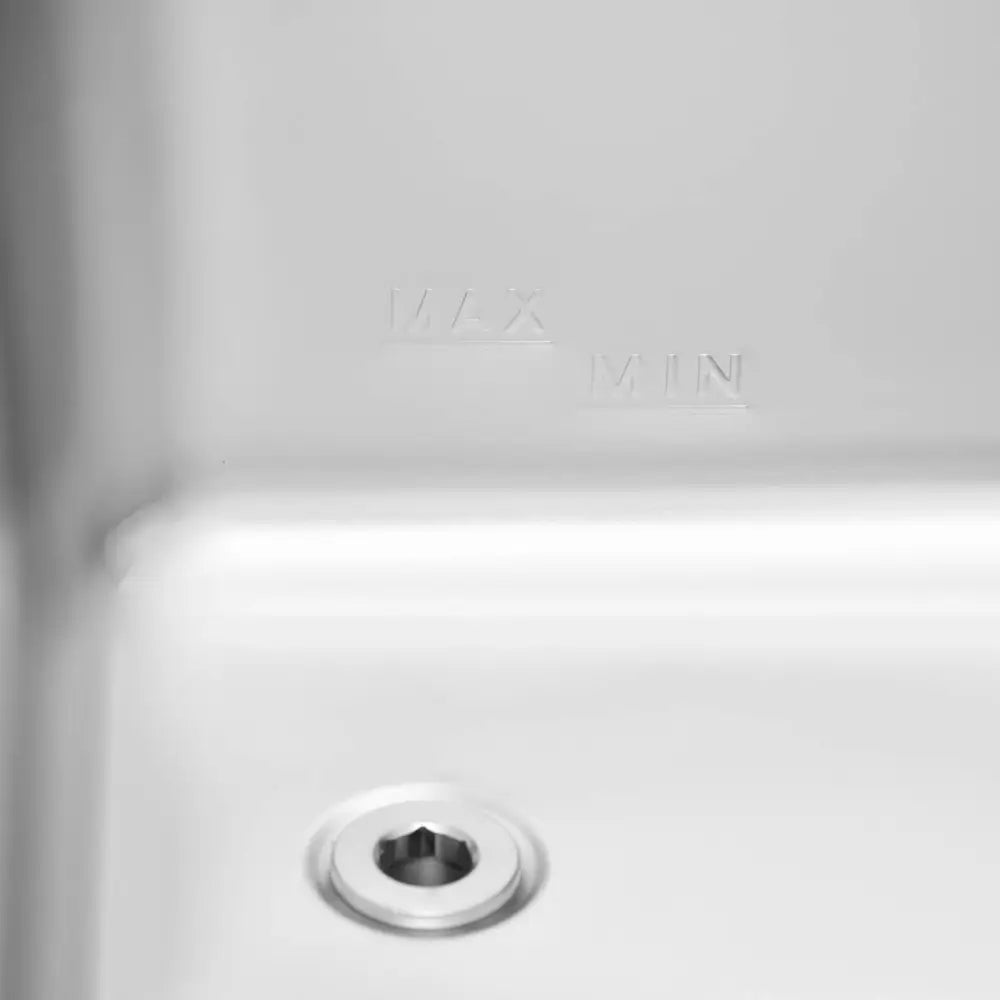 Elektrisk matvarmebeholder, nærbilde av innvendig metall med nivåmerkinger og sekskantet skrue i bunnen.