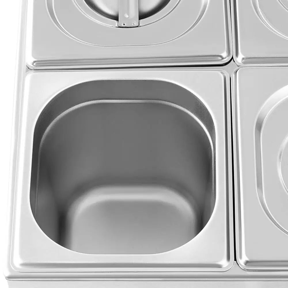 Elektrisk oppvarmingstreningsapparat med åpen firkantet stålfat, sett ovenfra blant lukkede beholdere.