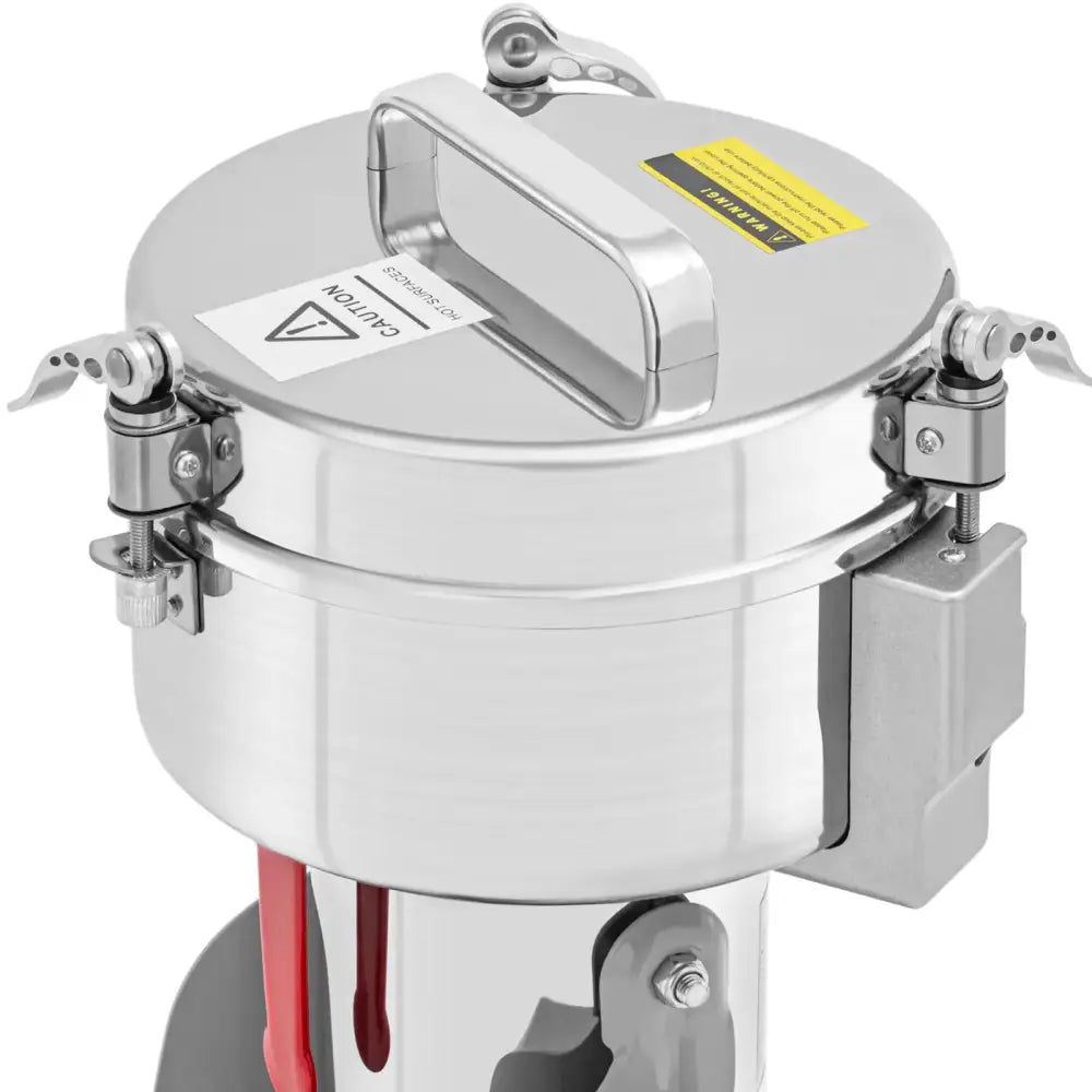 Elektrisk krydder- og urtemølle i rustfritt stål, sett fra skråvinkel med synlige advarselslapper på lokket.