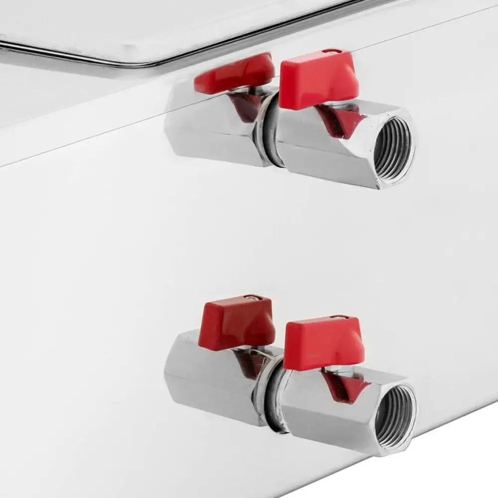 Elektrisk sjokoladesmelter, nærbilde av to metallventiler med røde håndtak på rustfri ståloverflate.