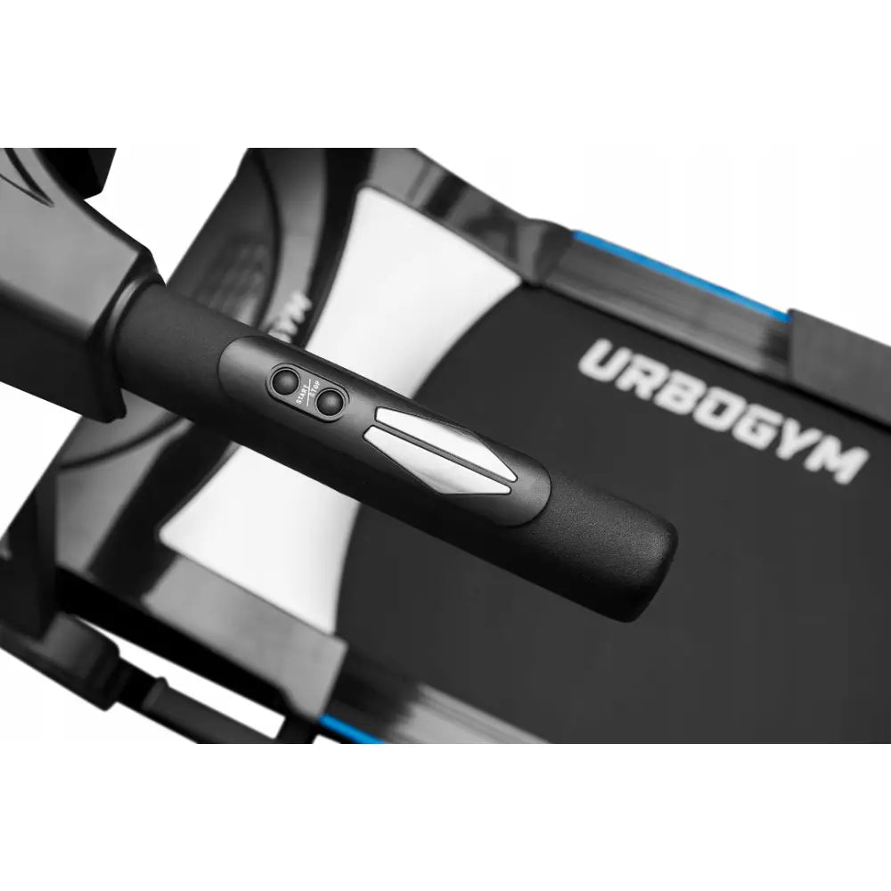Tredemølle Urbogym V520, nærbilde av sort håndtak med sølvknapp og kontrollpanel, URBOGYM-logo på båndet.