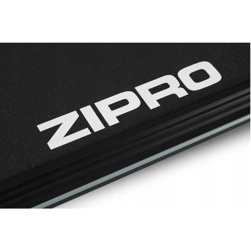 Tredemølle Zipro Colt, nærbilde av sort overflate med stor hvit logo, synlig lagstruktur og hvit stripe.