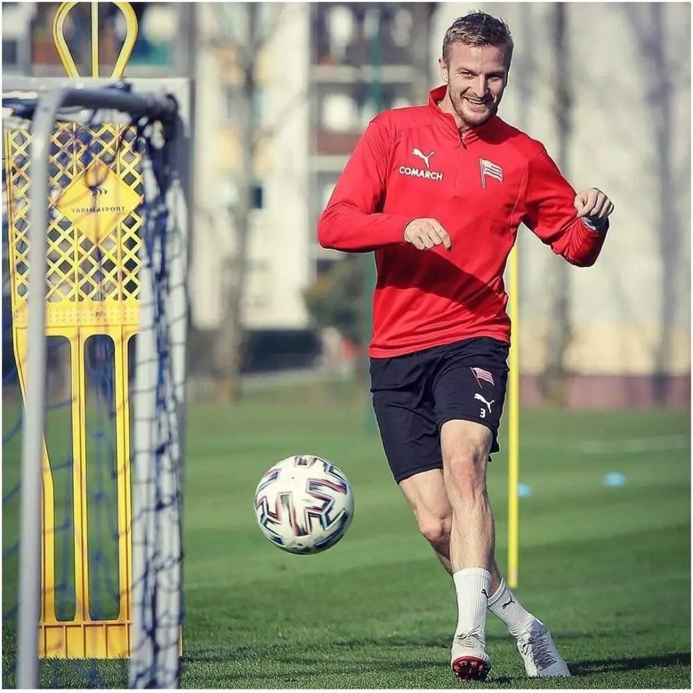 Elite fotballmål 180 cm blå, i bruk på gressbane med spiller i aksjon ved gul treningsfigur og ball.