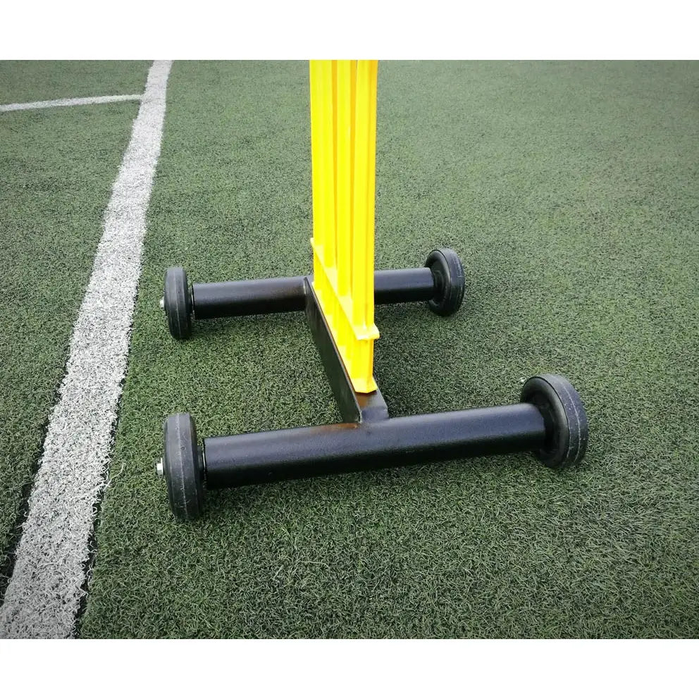 Elite fotballmurmester vogn, nærbilde av sort understell med hjul og gul plastdel på kunstgress med hvit linje.