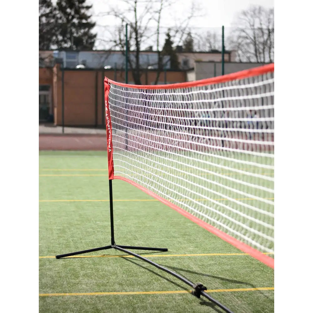 Elite Pro Indoor Volleyball Net Set, sidevisning av hvitt nett med røde kanter og svarte stenger på grønt kunstgress.