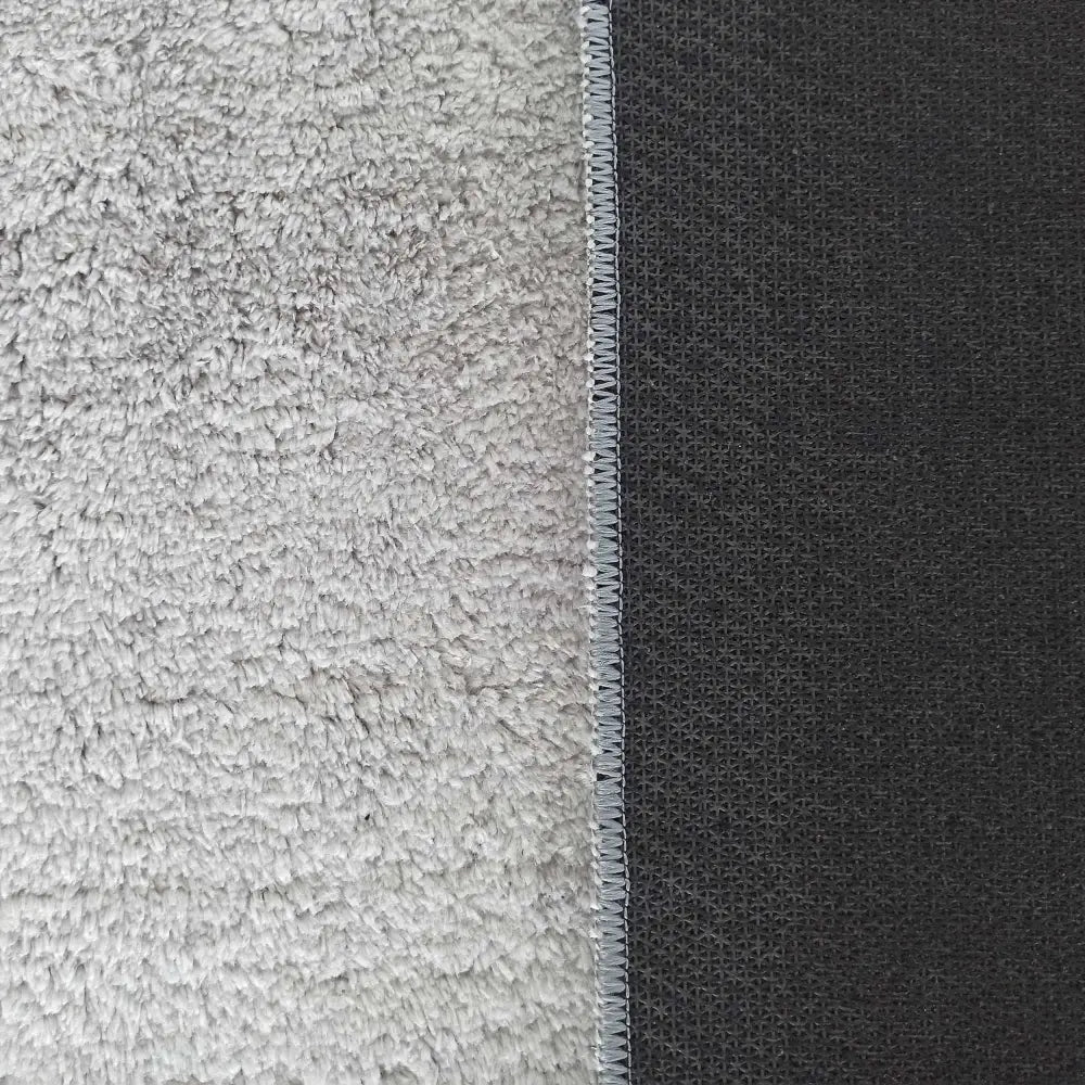 Enzo grå teppe 80 x 300 cm, detaljert nærbilde av myk lys grå overflate og mørk grå bakside med søm.