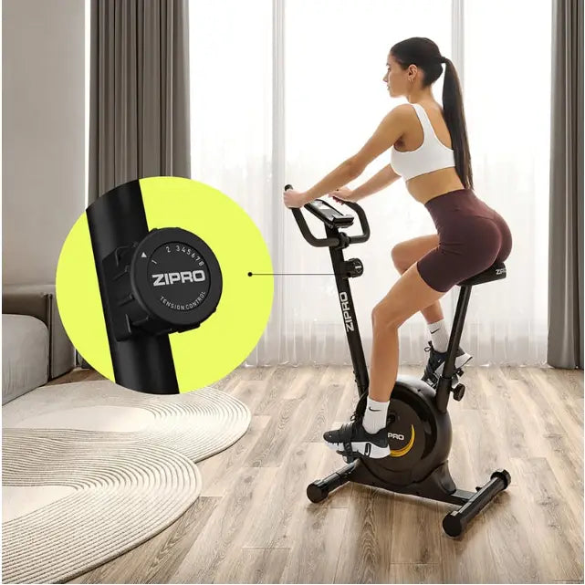 Ergometersykkel Zipro One, sidebilde med fokus på motstandsjustering og gule detaljer i moderne stue.