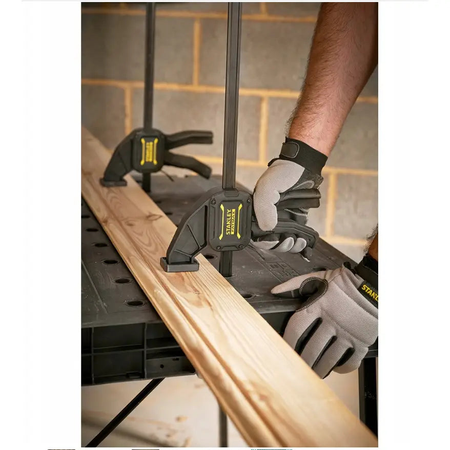 Essential arbeidsbord fra Stanley, brukt med håndklemmer for å feste treplanke, sett fra siden med hansker.