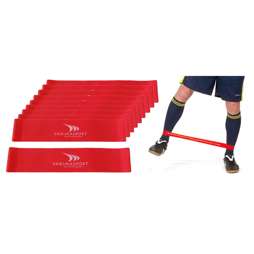 Fitnessgummi sett, røde treningsstrikker stablet med én strikk brukt rundt bena på person i shorts og sokker.